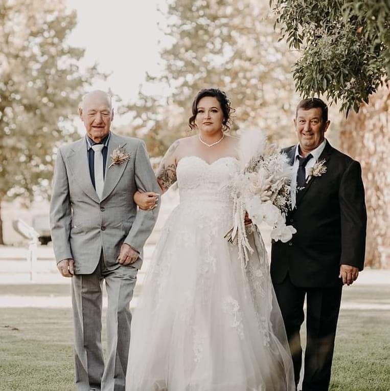 Taylor being walked into the wedding ceremony with her dad and grandfather